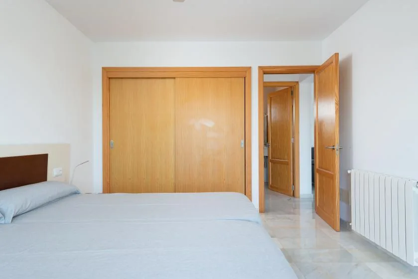 Un dormitorio con una cama, puertas de armario de madera y una puerta abierta.
