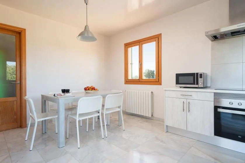 Una cocina luminosa con zona de comedor, ventana y electrodomésticos.