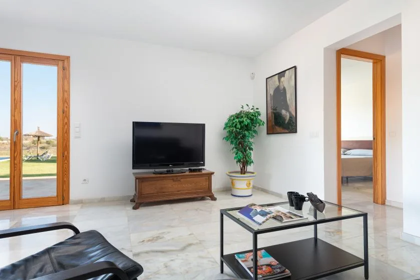 Una sala luminosa con televisor, asientos y una mesa de centro.