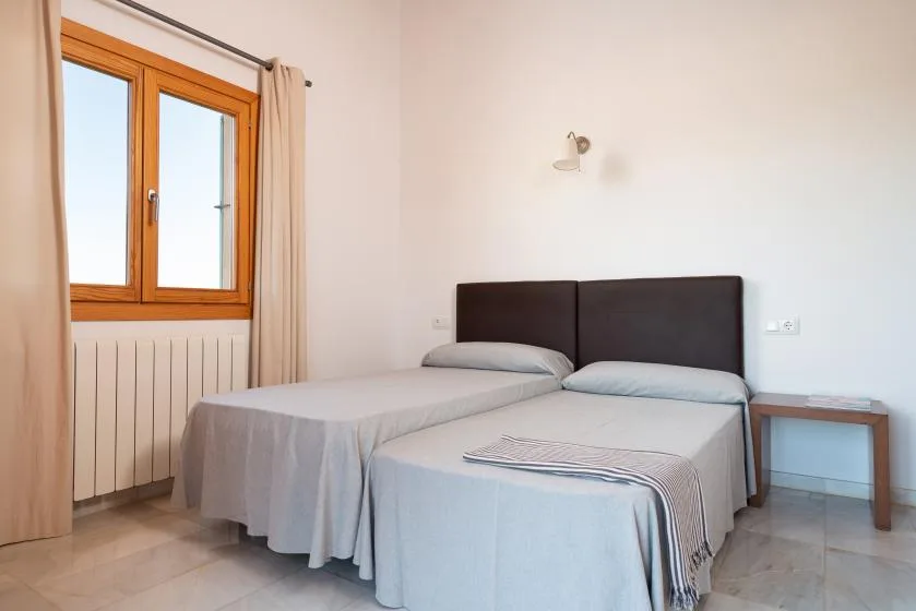 Un dormitorio con dos camas, una ventana y una pequeña mesa auxiliar.