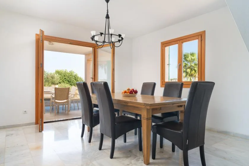 Un comedor con una mesa de madera y asientos tapizados oscuros.