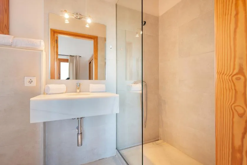 Un baño con lavabo de pared y una ducha de vidrio.