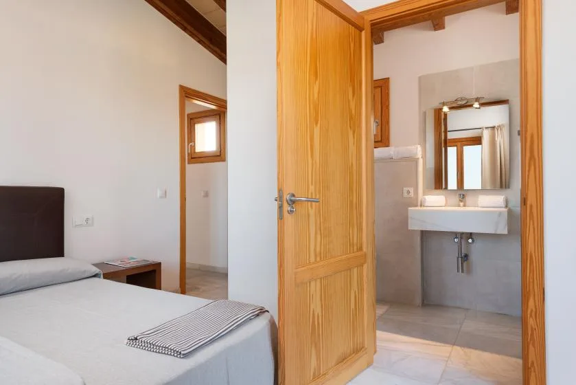 Un dormitorio con una cama y una puerta abierta hacia un baño.