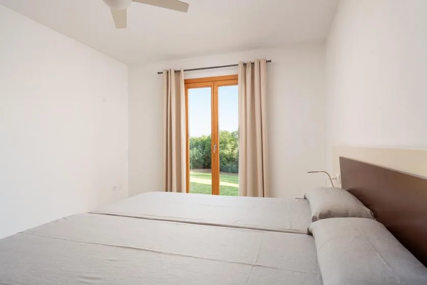 Un dormitorio luminoso con una cama frente a una puerta acristalada con cortinas.