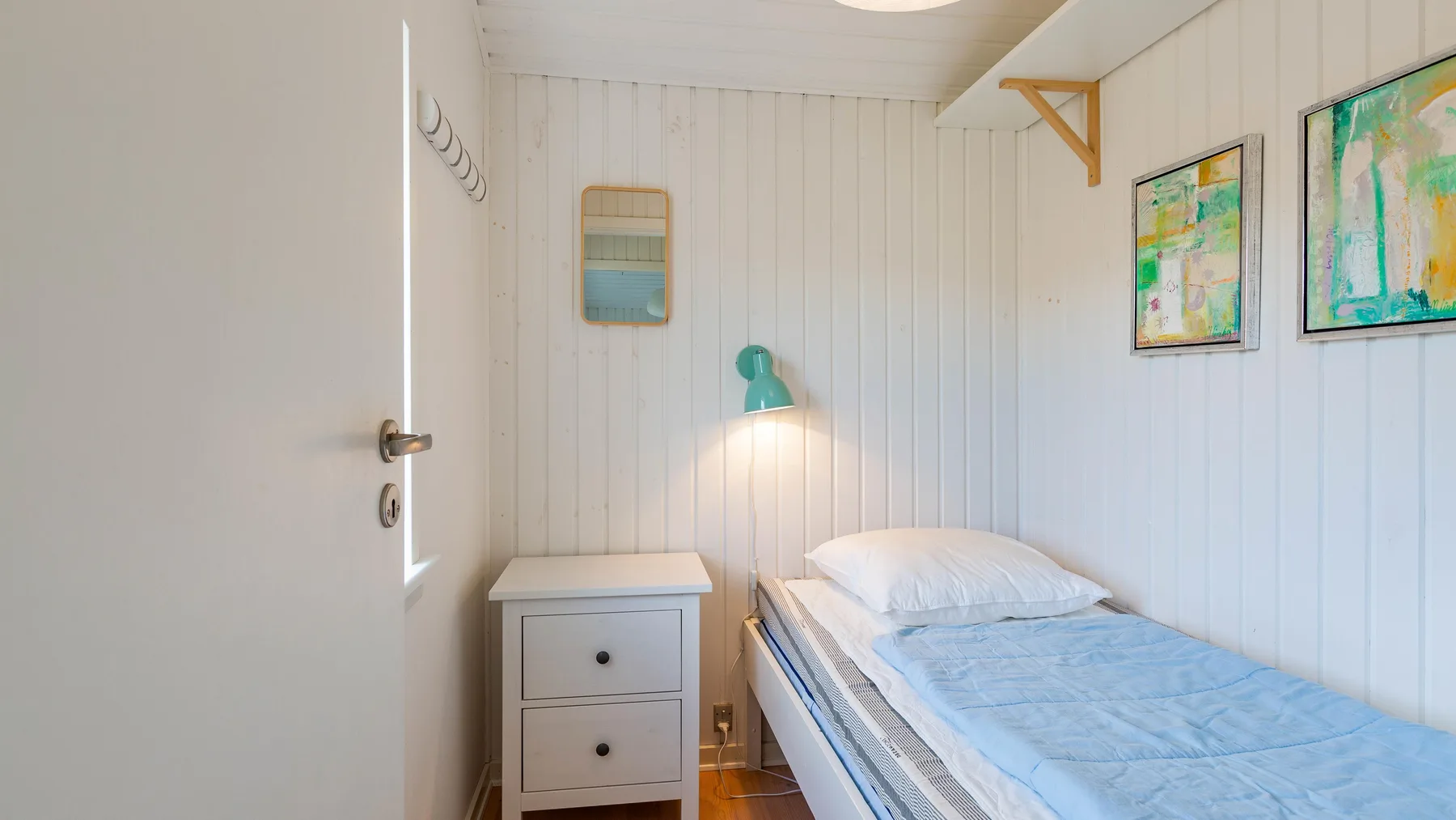 Un dormitorio luminoso con una cama individual y una mesita de noche.