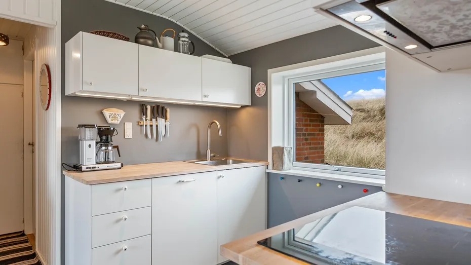 Una cocina moderna con gabinetes blancos y una ventana grande.