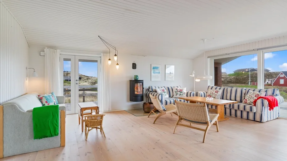 Una sala luminosa con asientos a rayas y grandes ventanas con vistas al paisaje.