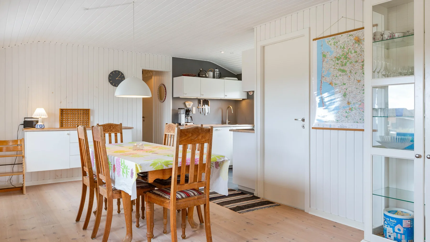 Comedor con una mesa y sillas de madera junto a una cocina luminosa.