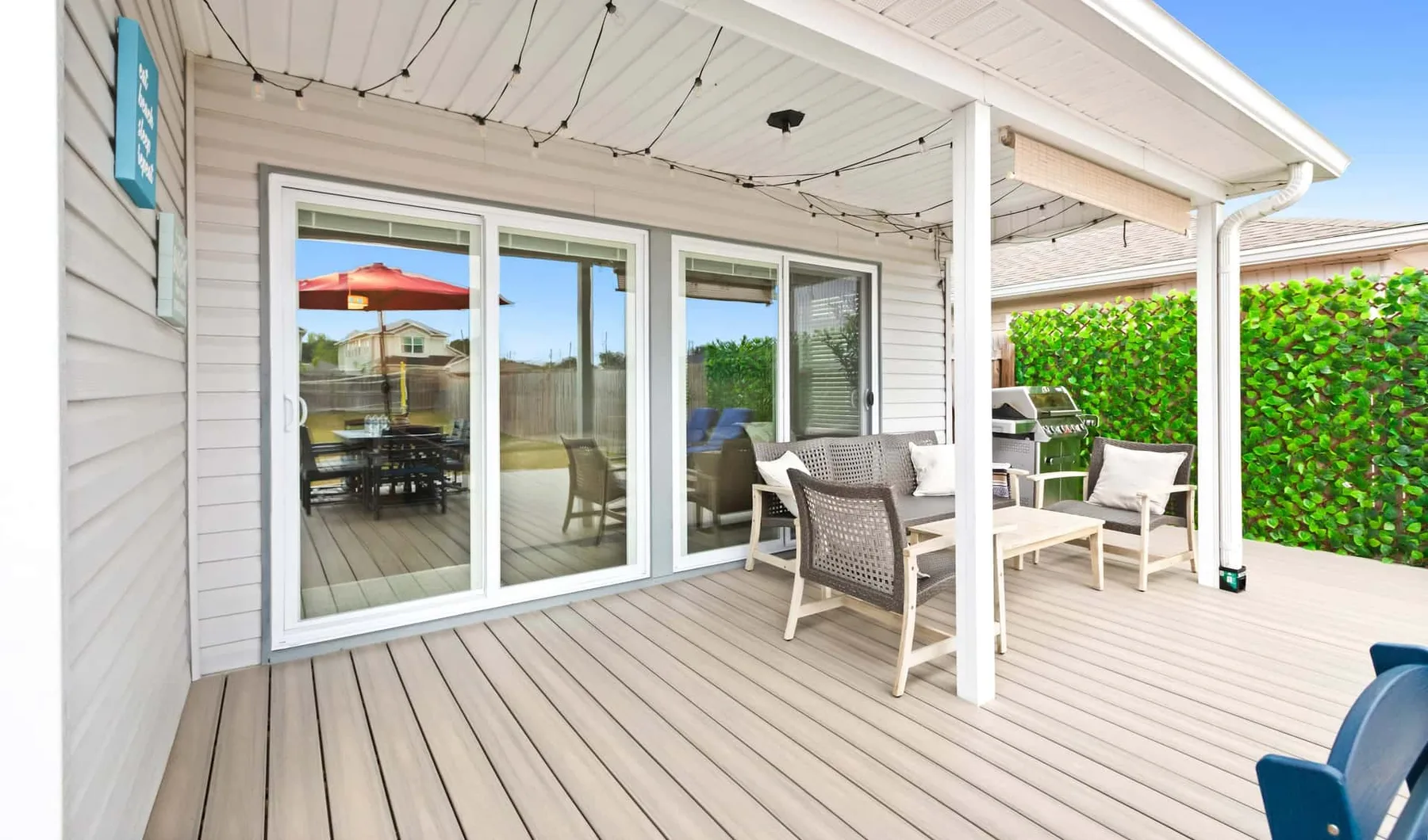 A covered outdoor deck with seating and sliding glass doors.