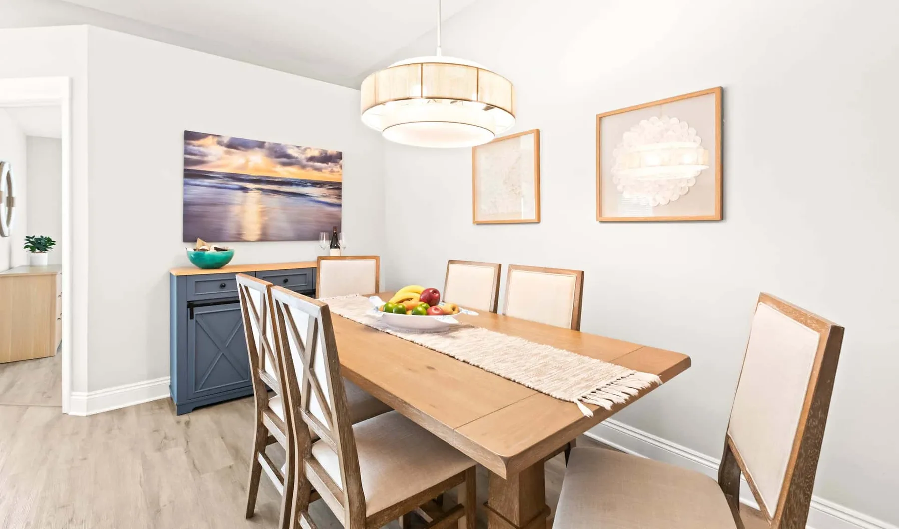 A dining room with a wooden table, upholstered seating, and framed wall art.