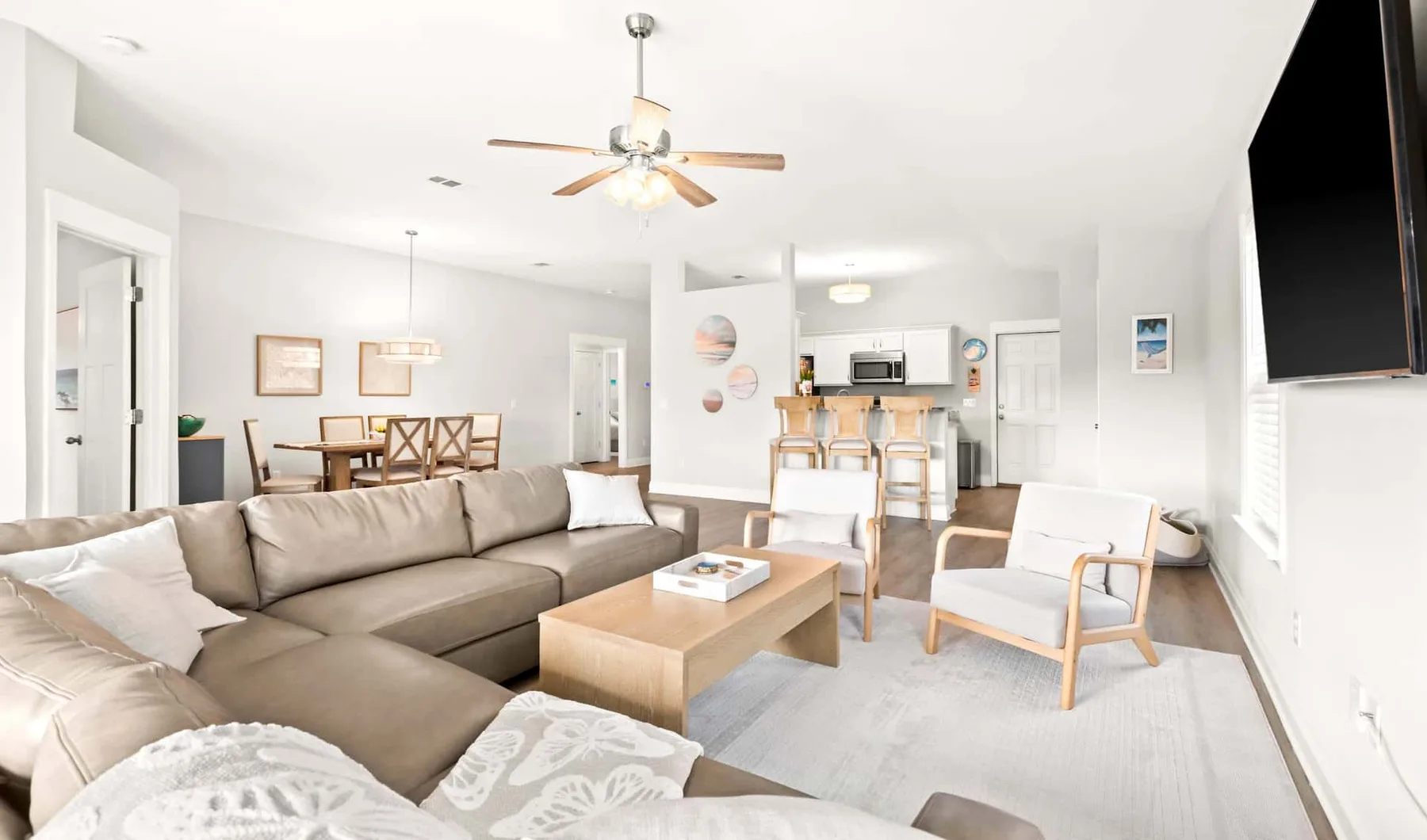 A bright living room with a sectional seating area and an open kitchen.