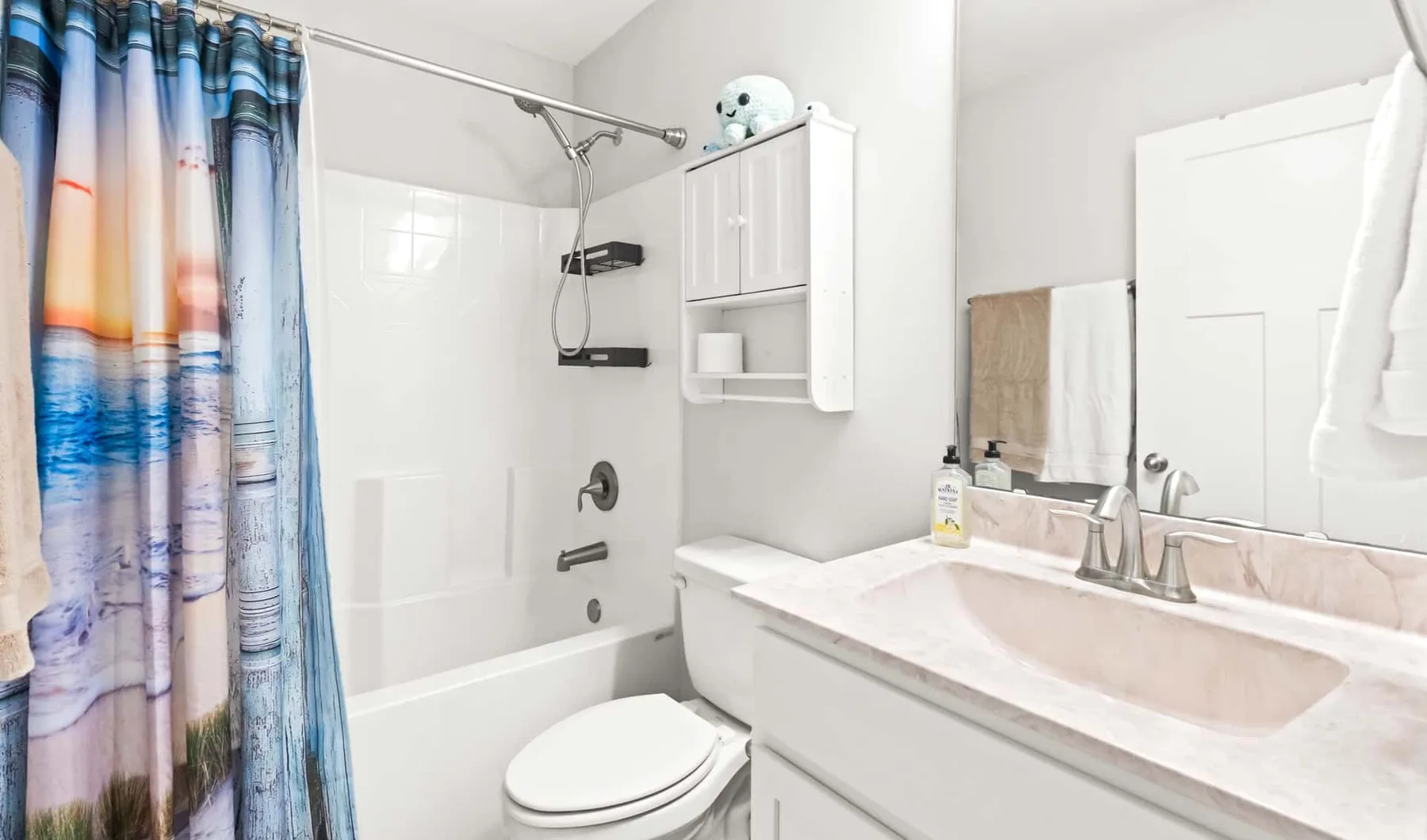 A bathroom with a bathtub, toilet, and sink beneath a mirror.