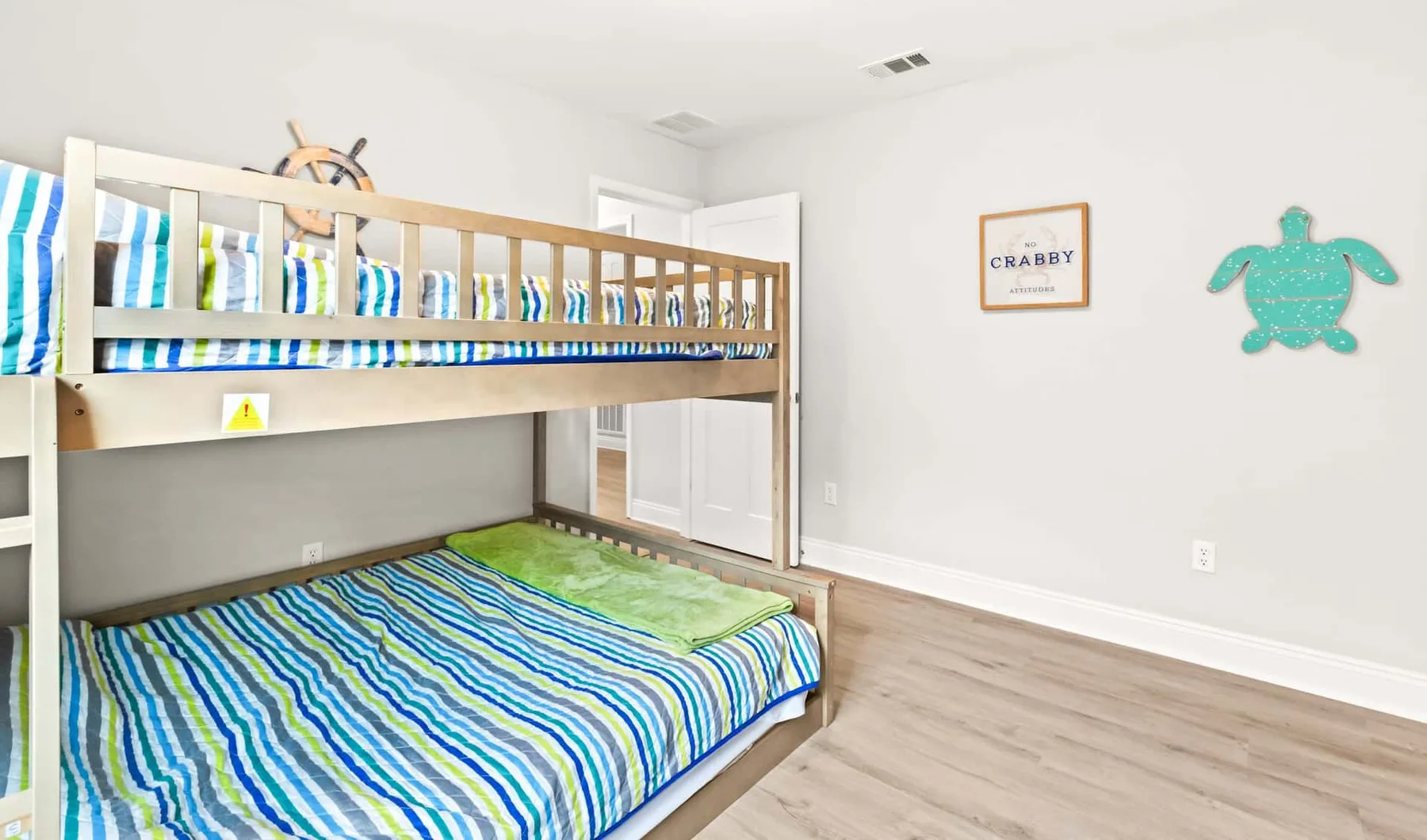 A bedroom with a wooden bunk bed dressed in blue, green, and white striped bedding.