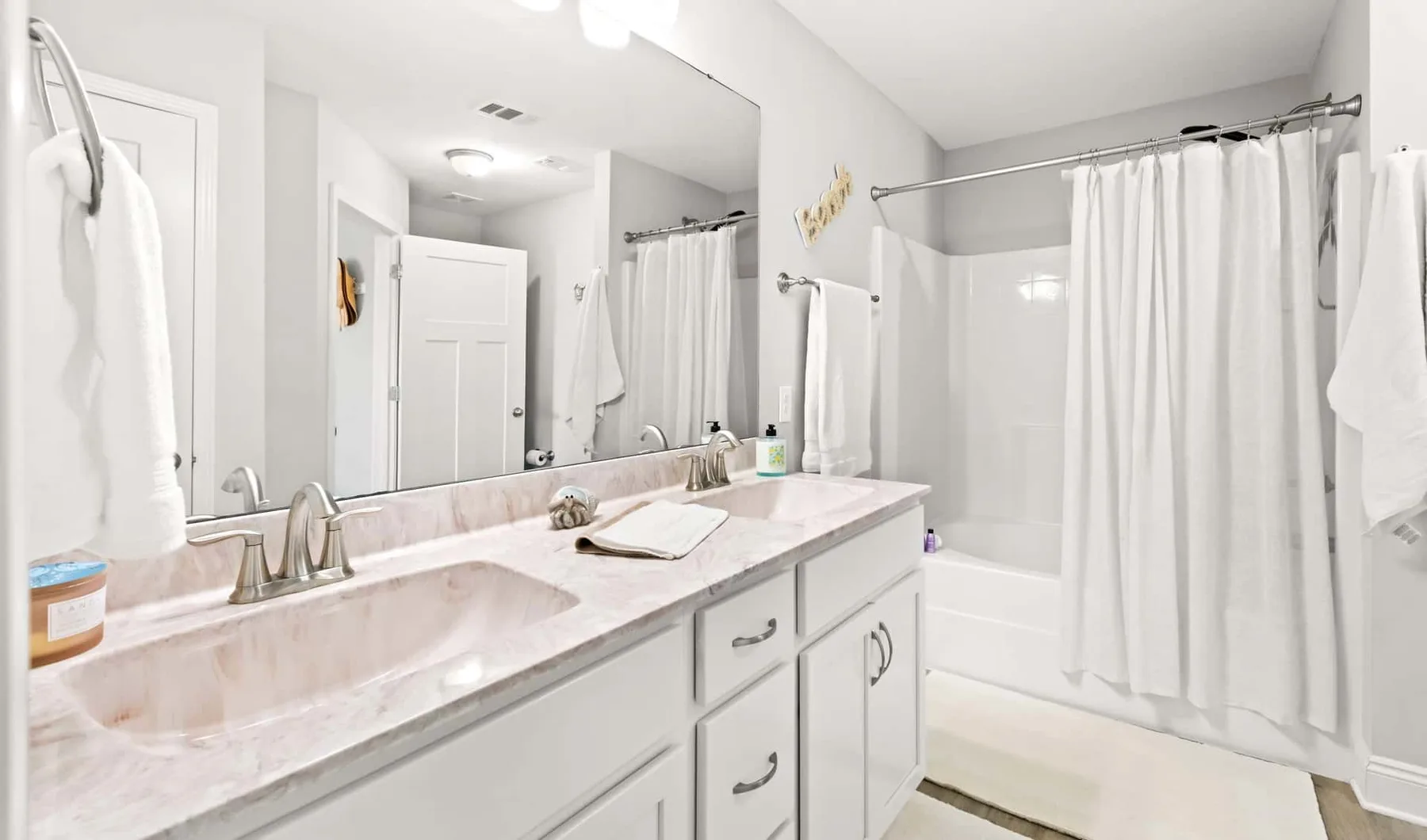 Bathroom with a long vanity and a curtained bathtub.