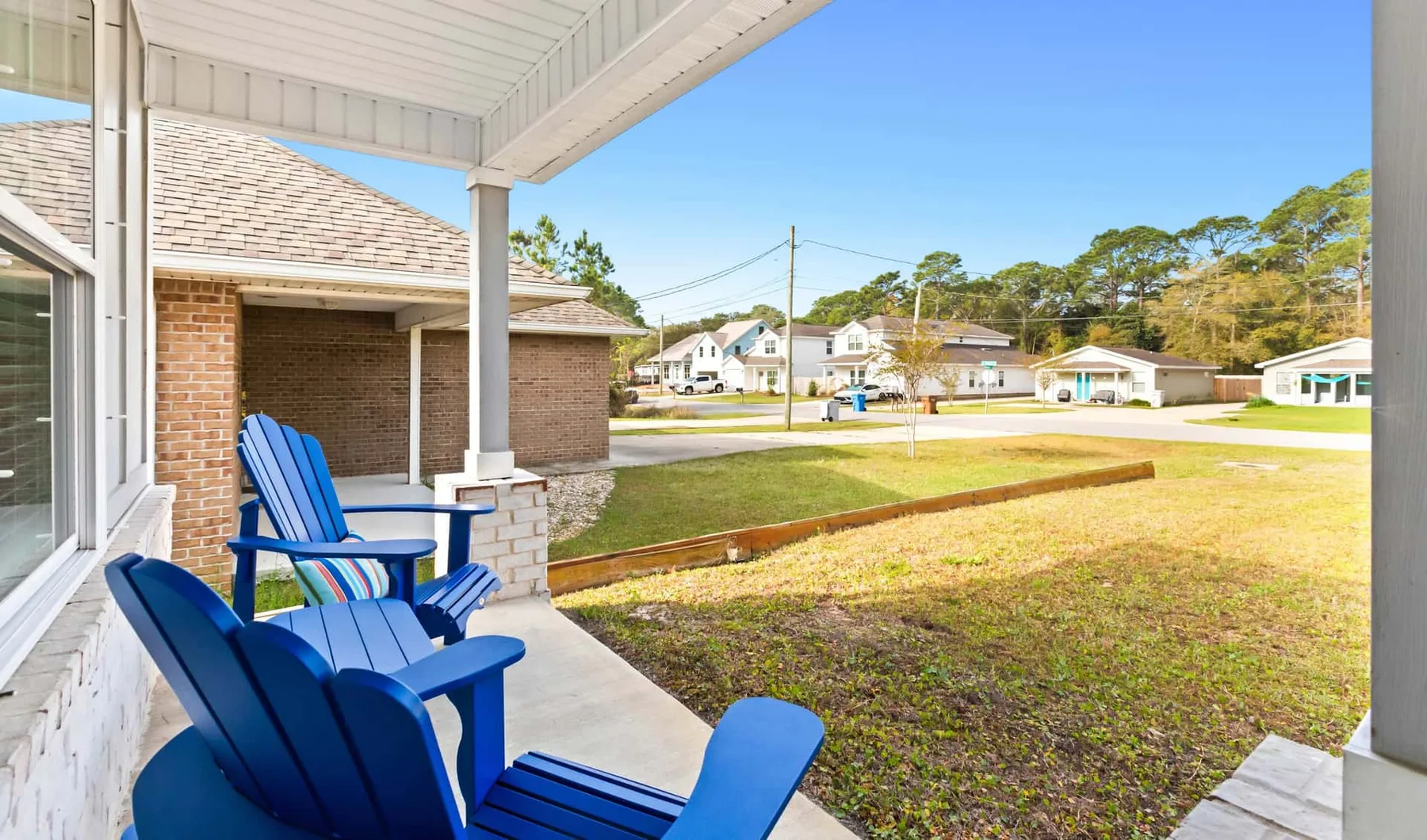 A covered patio with blue seating overlooks a grassy yard.