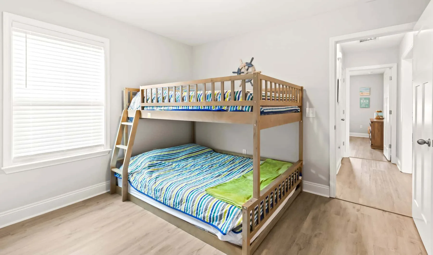 A bedroom with a wooden bunk bed and a large window.