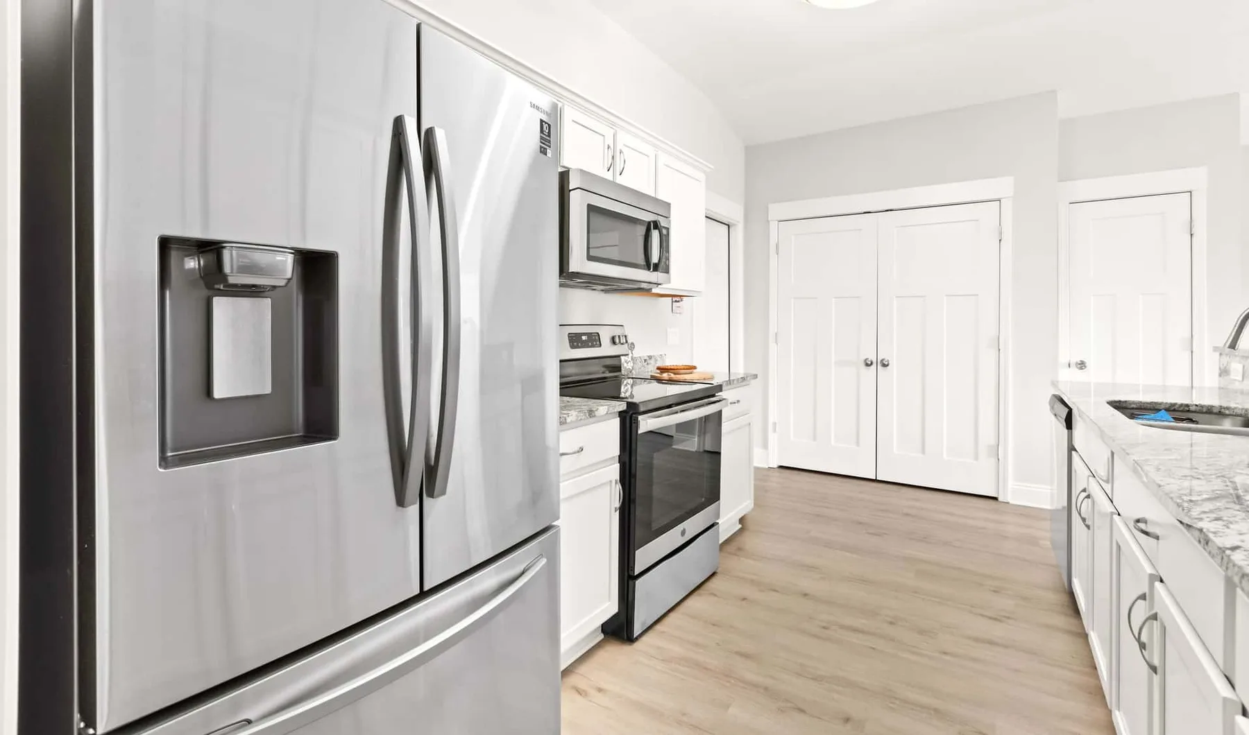 A bright kitchen with stainless steel appliances and white cabinetry.