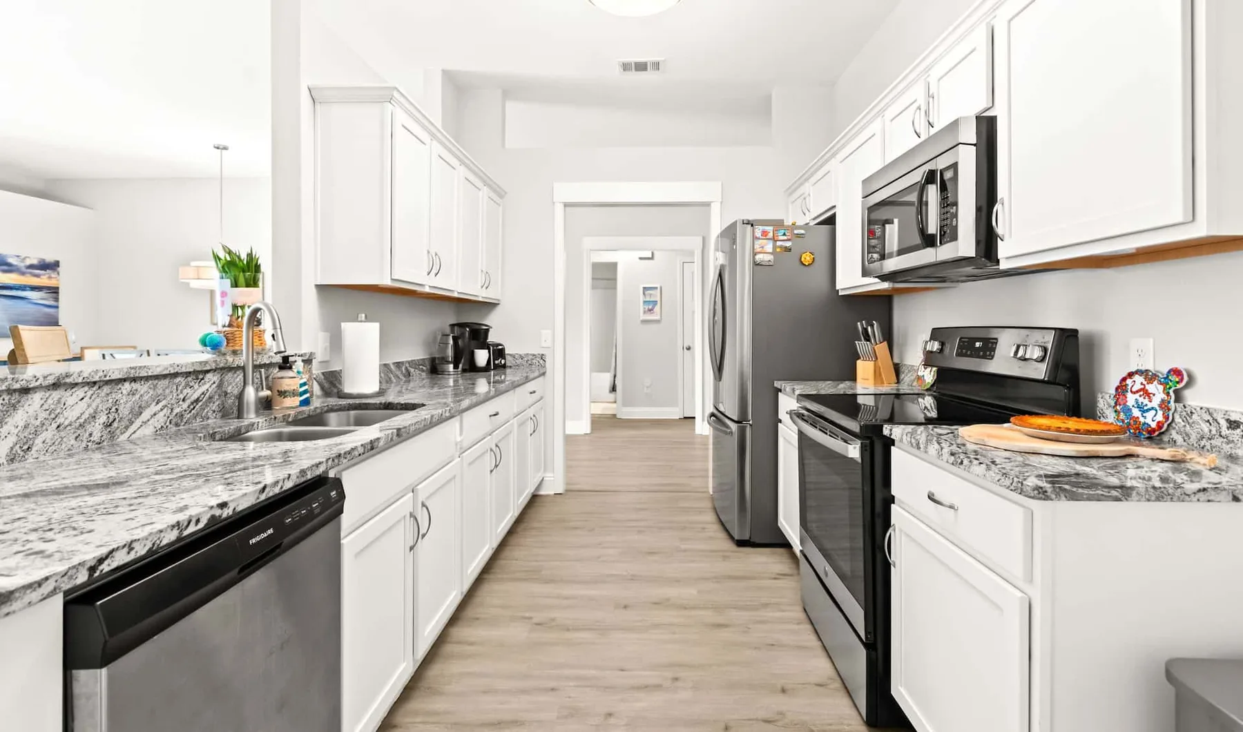 A bright kitchen with white cabinetry, stone countertops, and stainless steel appliances.