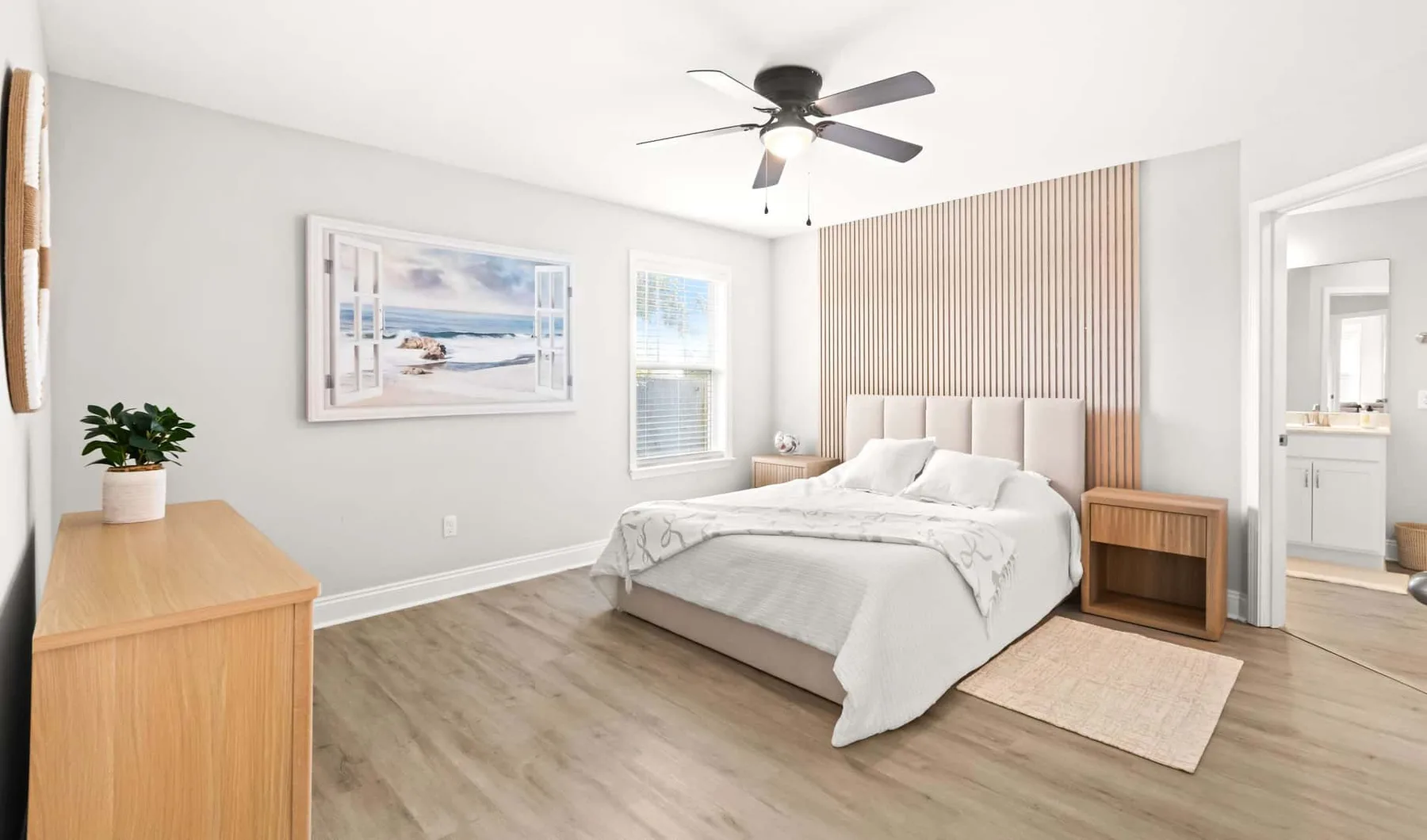 A bright bedroom with a bed, wall art, and a ceiling fan.