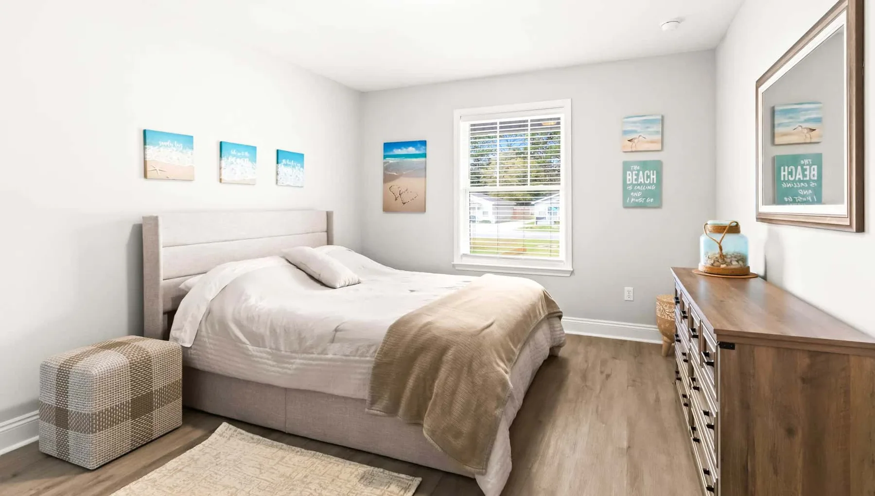 A bedroom with a neatly made bed and a window with blinds.