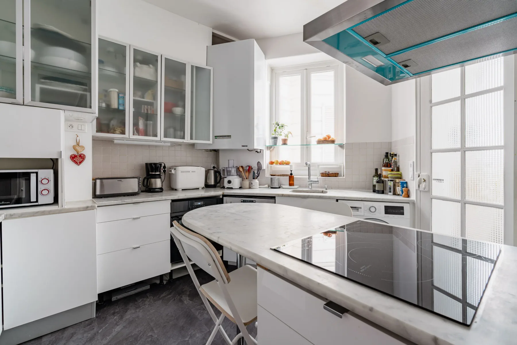 Una cocina luminosa con armarios blancos y una isla central.