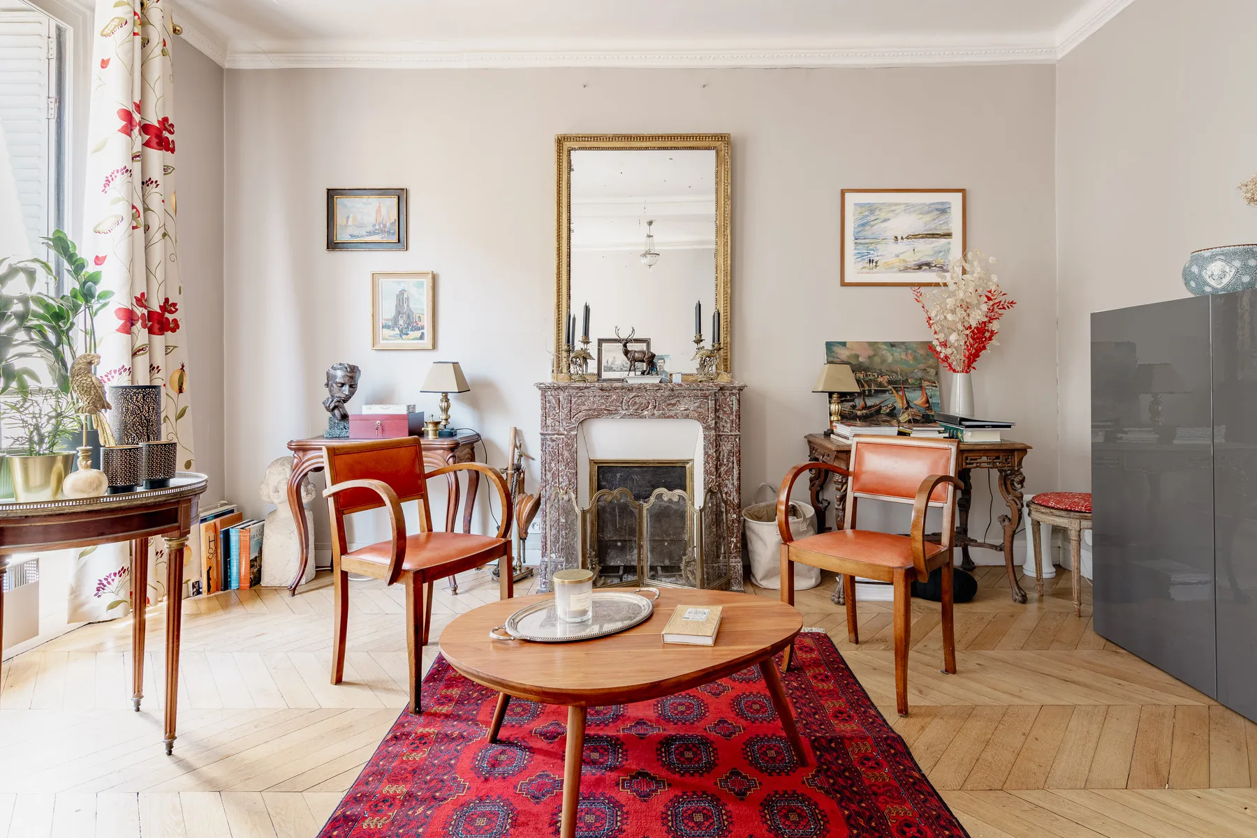 Una sala luminosa con chimenea, asientos y una alfombra roja estampada.
