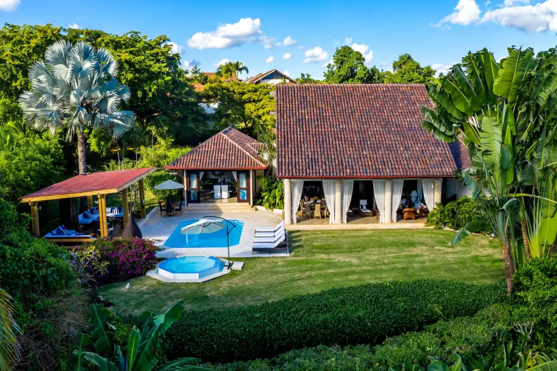 Una propiedad tropical ajardinada con edificios alrededor de una piscina.