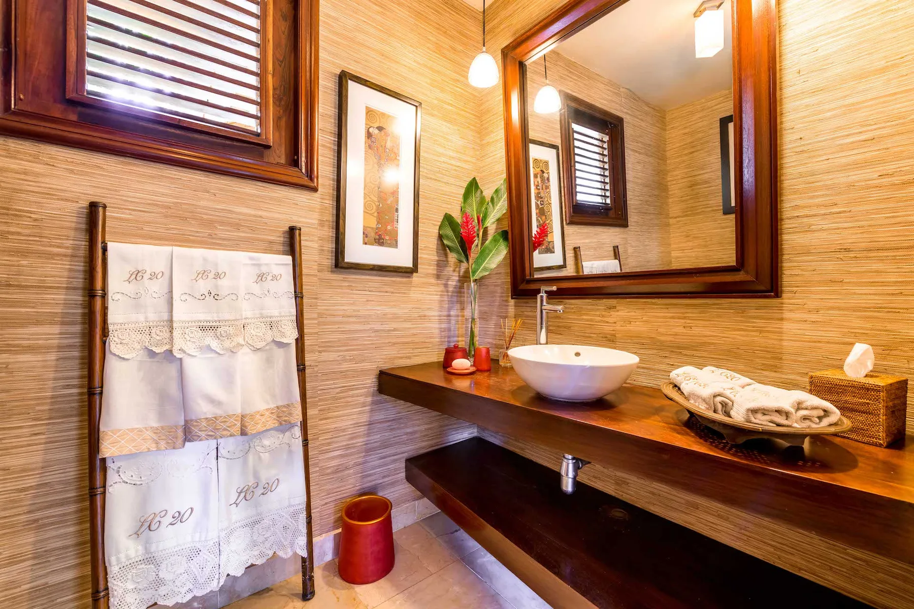 Un baño de tonos cálidos con lavabo, mueble de madera y un espejo grande.