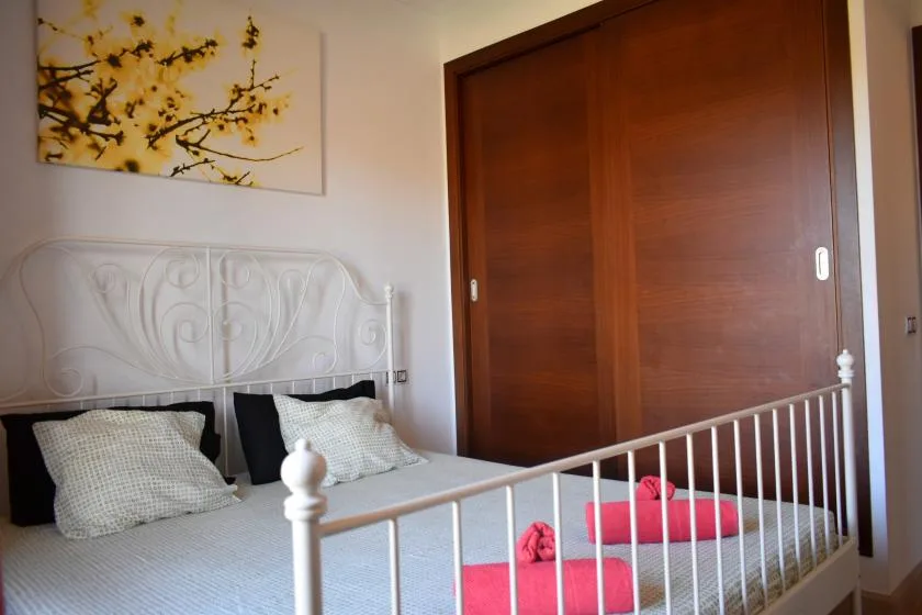 Un dormitorio con una cama blanca y una gran puerta corrediza de armario de madera.