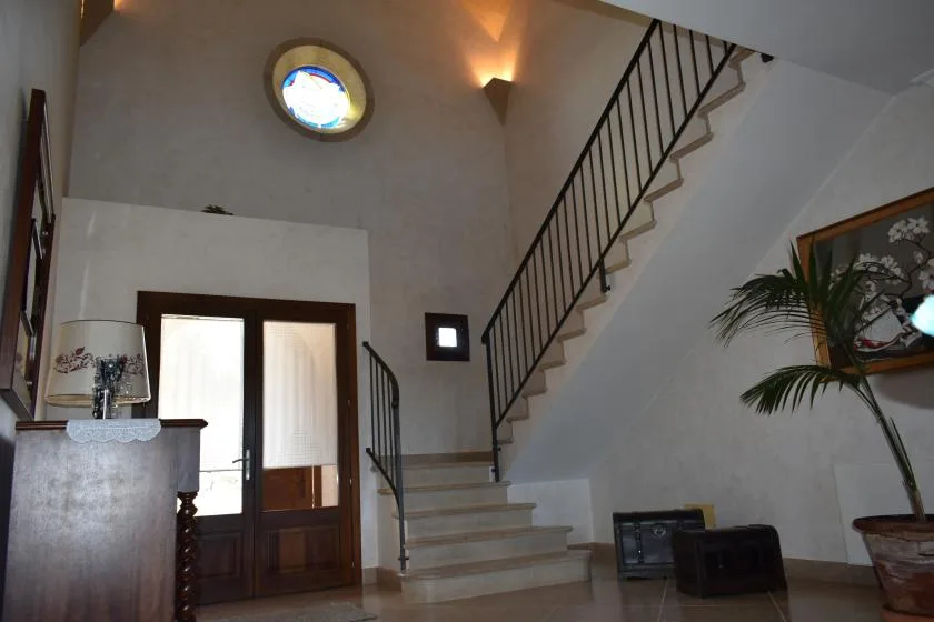 Un recibidor luminoso con una escalera y una ventana redonda.