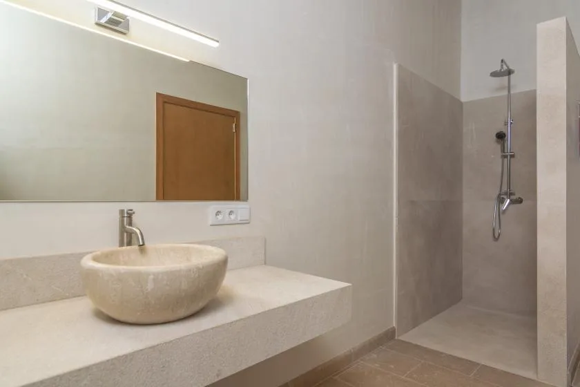 Un baño moderno con un lavabo sobre encimera y una zona de ducha abierta.