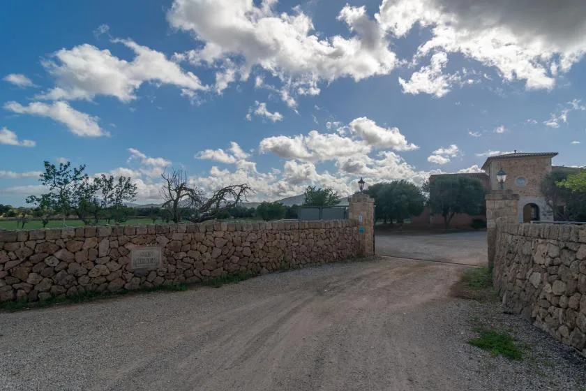 Un camino de grava pasa por una entrada de piedra junto a un edificio de piedra.
