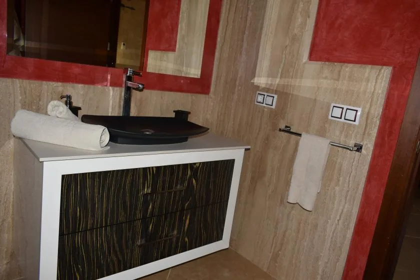 Un tocador de baño con un lavabo oscuro y una toalla colgada en la pared.