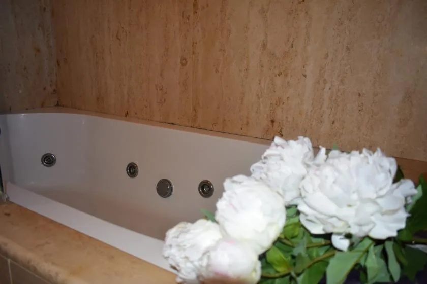Una bañera con chorros está junto a un grupo de flores blancas.