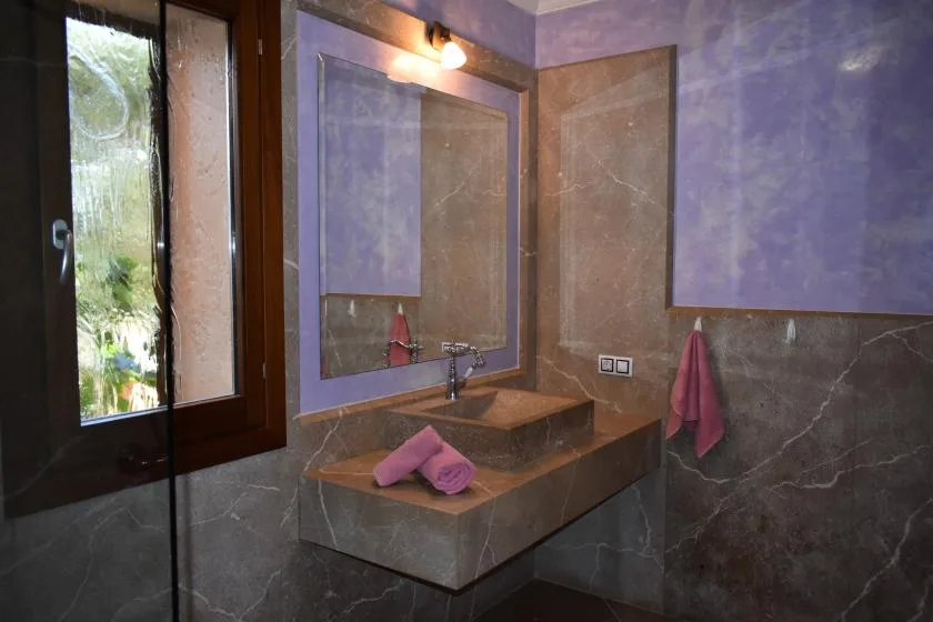 Un lavabo de baño con espejo, cuenco y ventana.