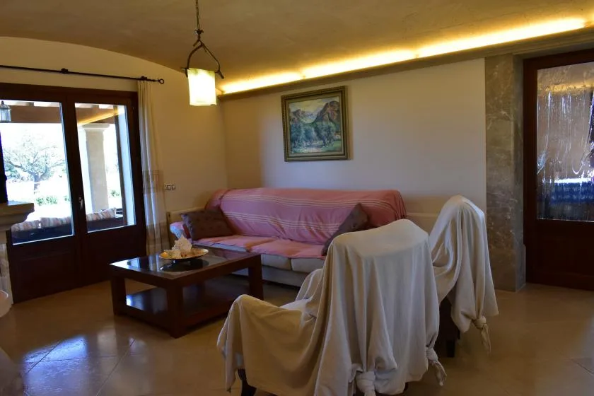 Una sala de estar con sofá, mesa de centro y asientos cubiertos.