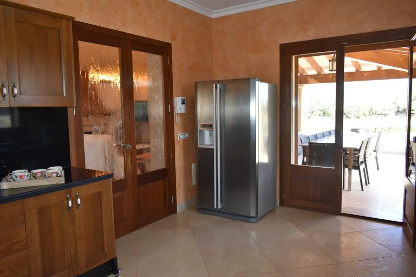 Una cocina con armarios de madera y un refrigerador junto a puertas de vidrio.