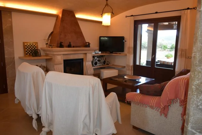 Una sala de estar con asientos cubiertos, una chimenea y puertas de vidrio que dan a un patio.
