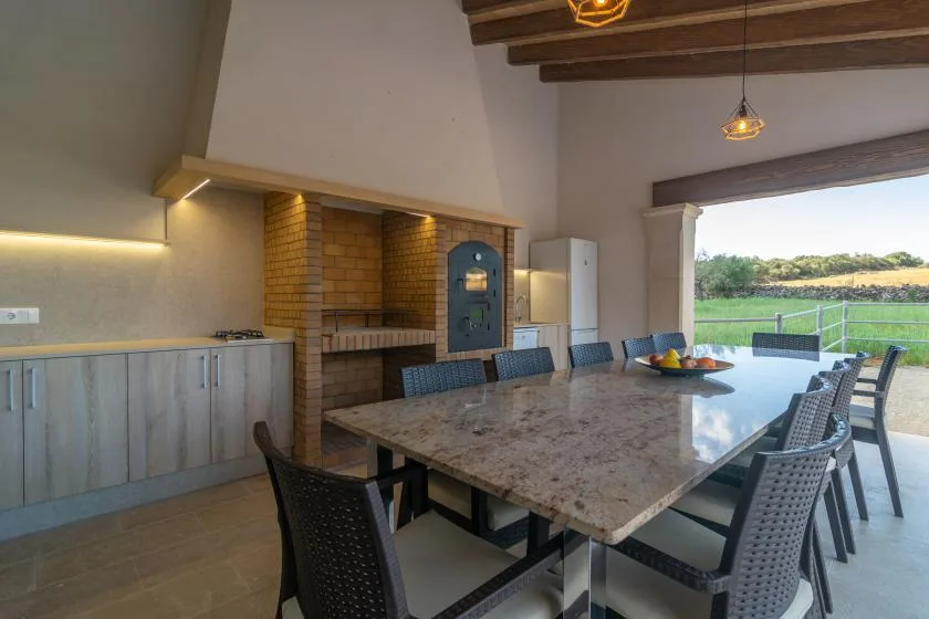 Un amplio comedor con una mesa grande, asientos y un rincón de cocina de ladrillo.