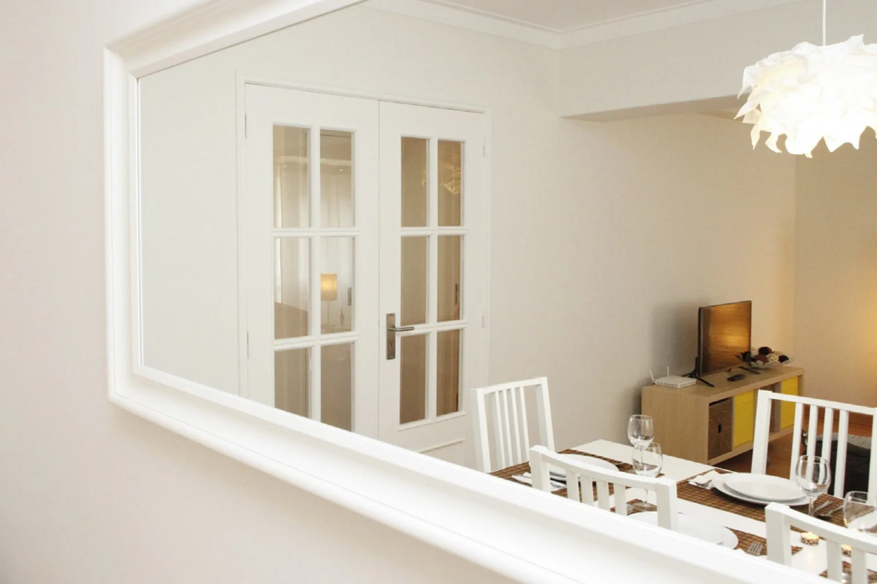 A dining area with white seating and a television.