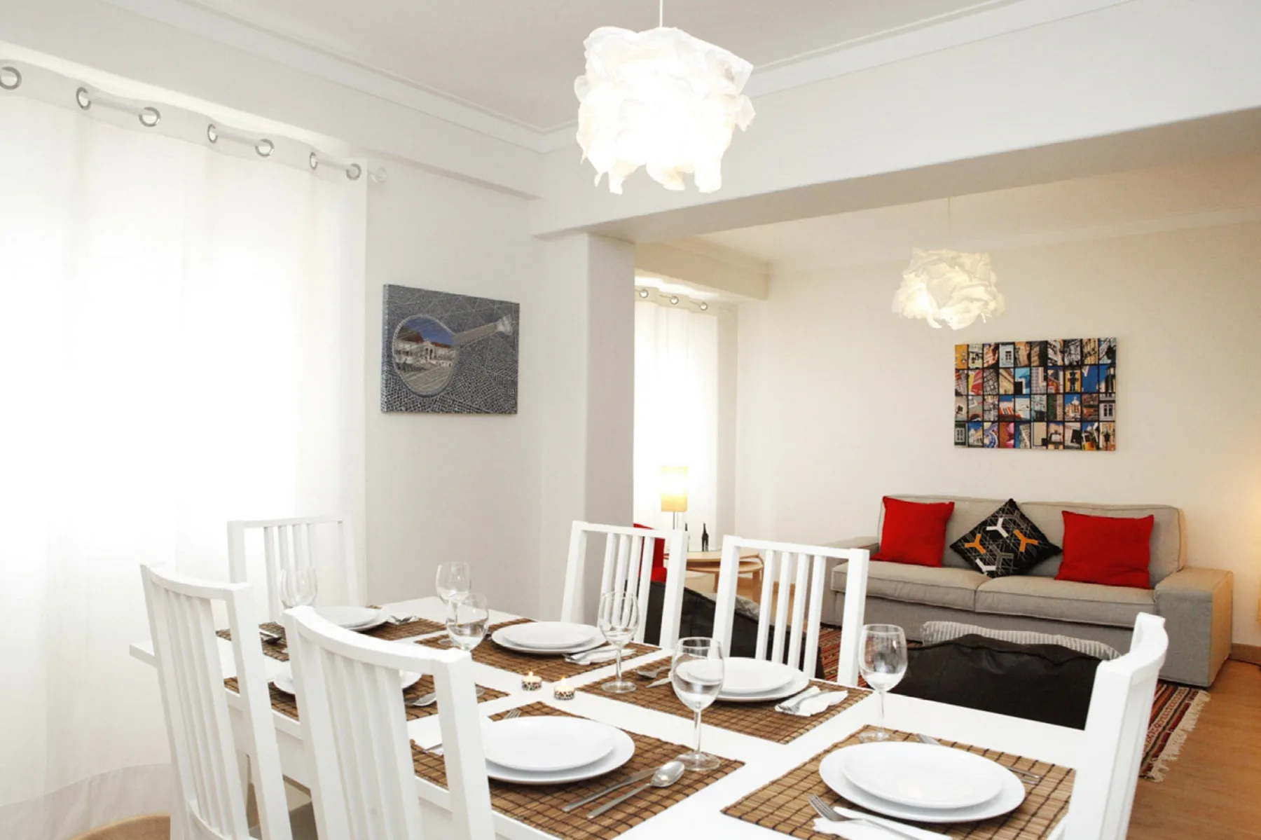A dining area with a set table sits beside a living room with seating.
