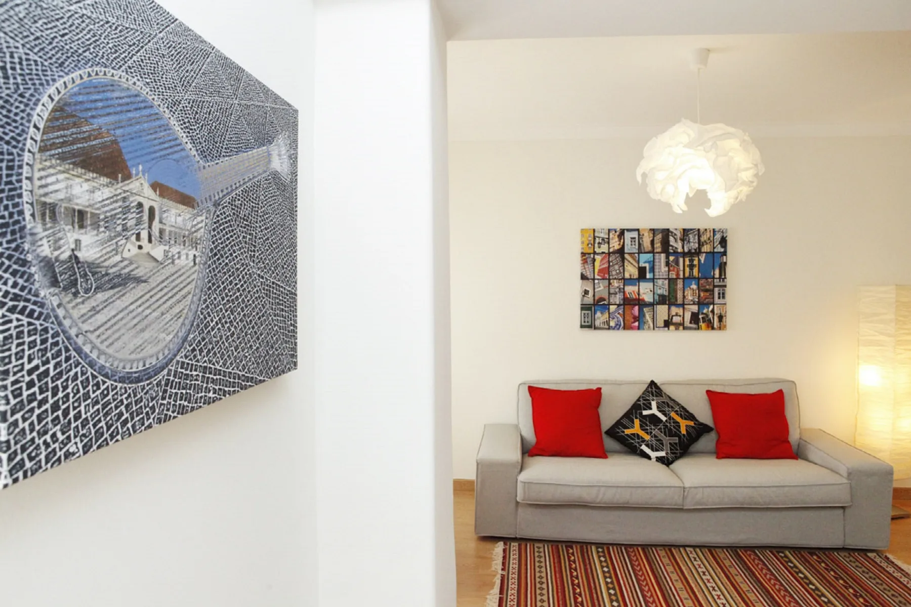 Living room with a sofa, colorful wall art, and a patterned rug.