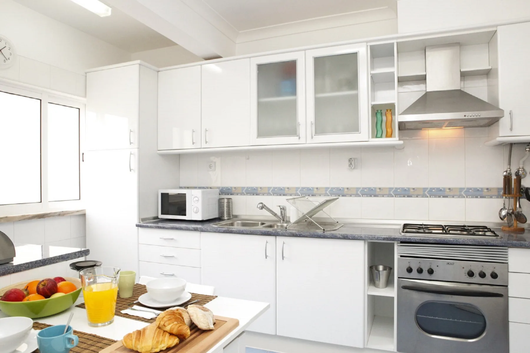 A bright kitchen with white cabinets, a countertop, and a dining table.