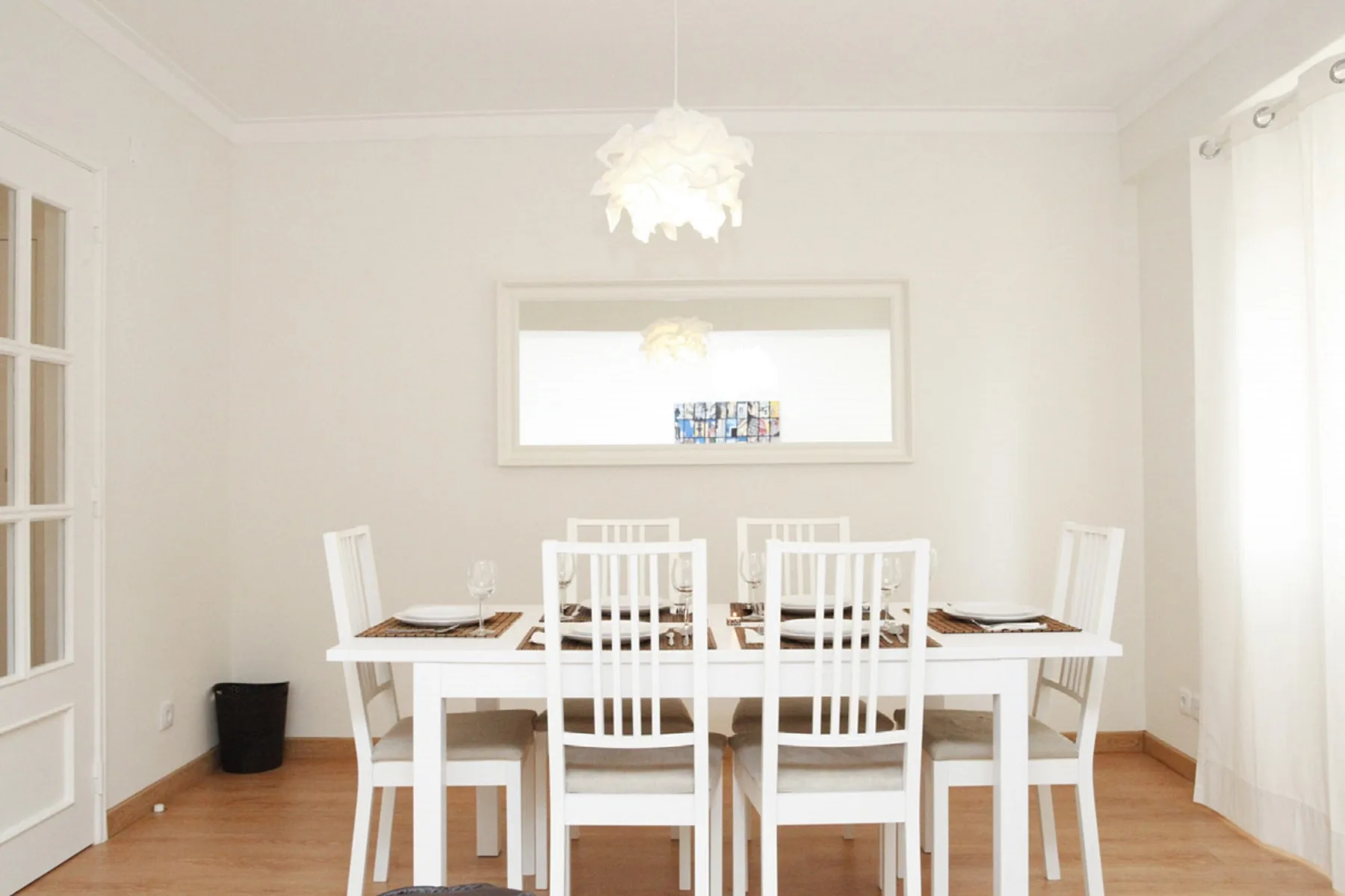 Comedor con una mesa blanca y sillas bajo una lámpara colgante.