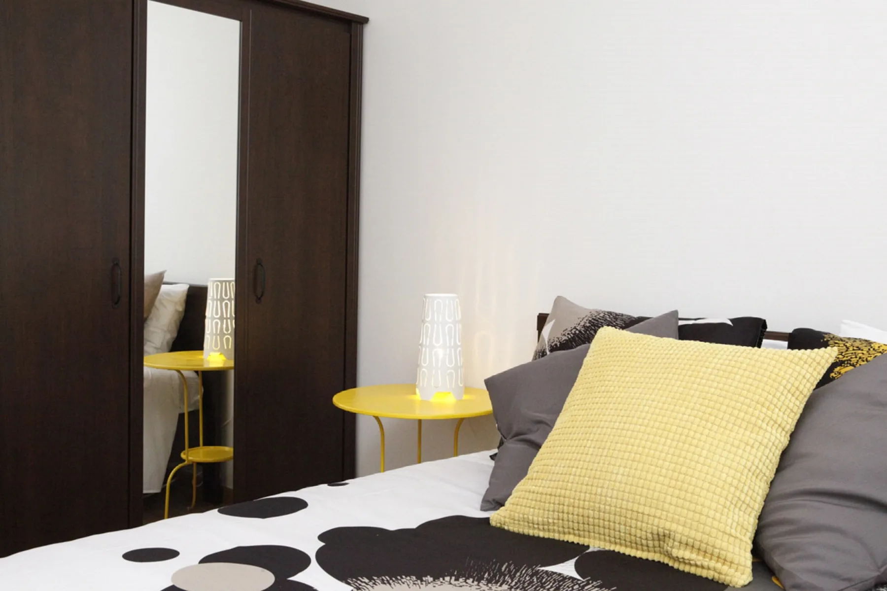A bedroom with a bed and dark wardrobe.