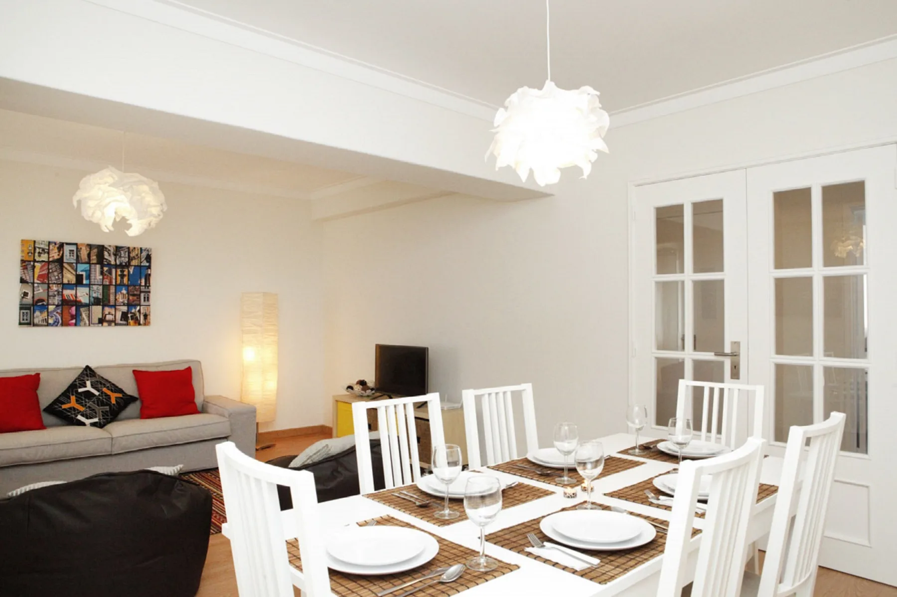 Un comedor luminoso con la mesa puesta y asientos junto a la sala de estar.