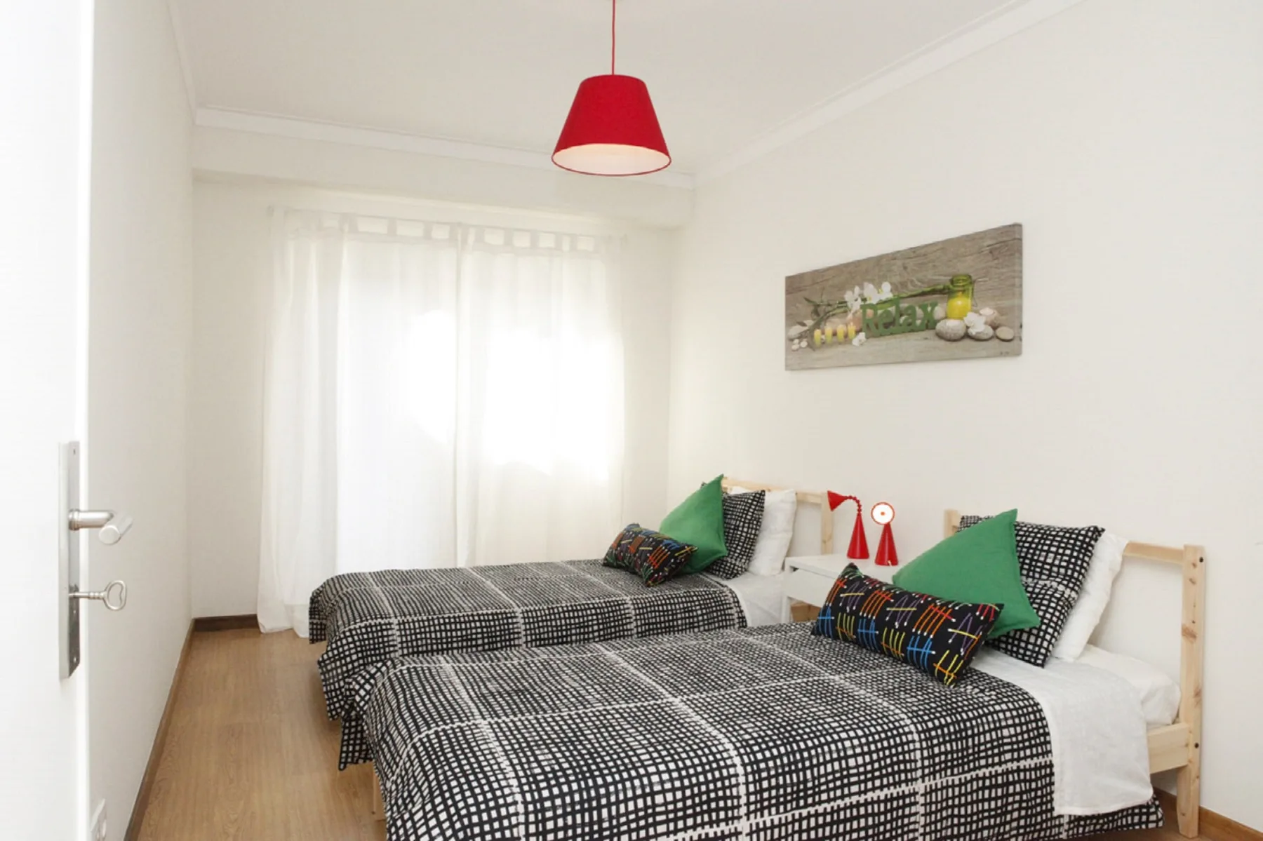 A bright bedroom with two beds dressed in black-and-white checked bedding.