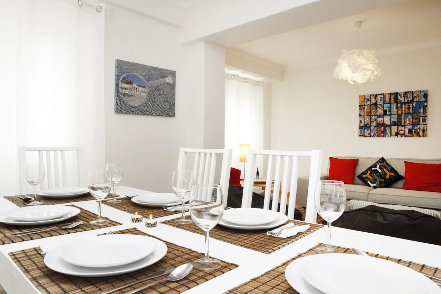 Una mesa preparada para comer está frente a una zona de estar con cojines rojos.