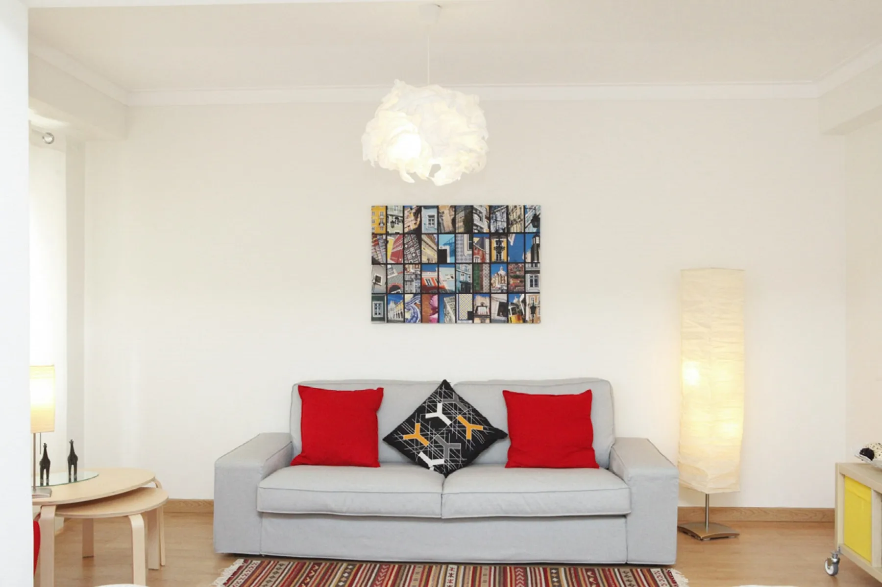 A living room with a gray sofa and colorful artwork on the wall.