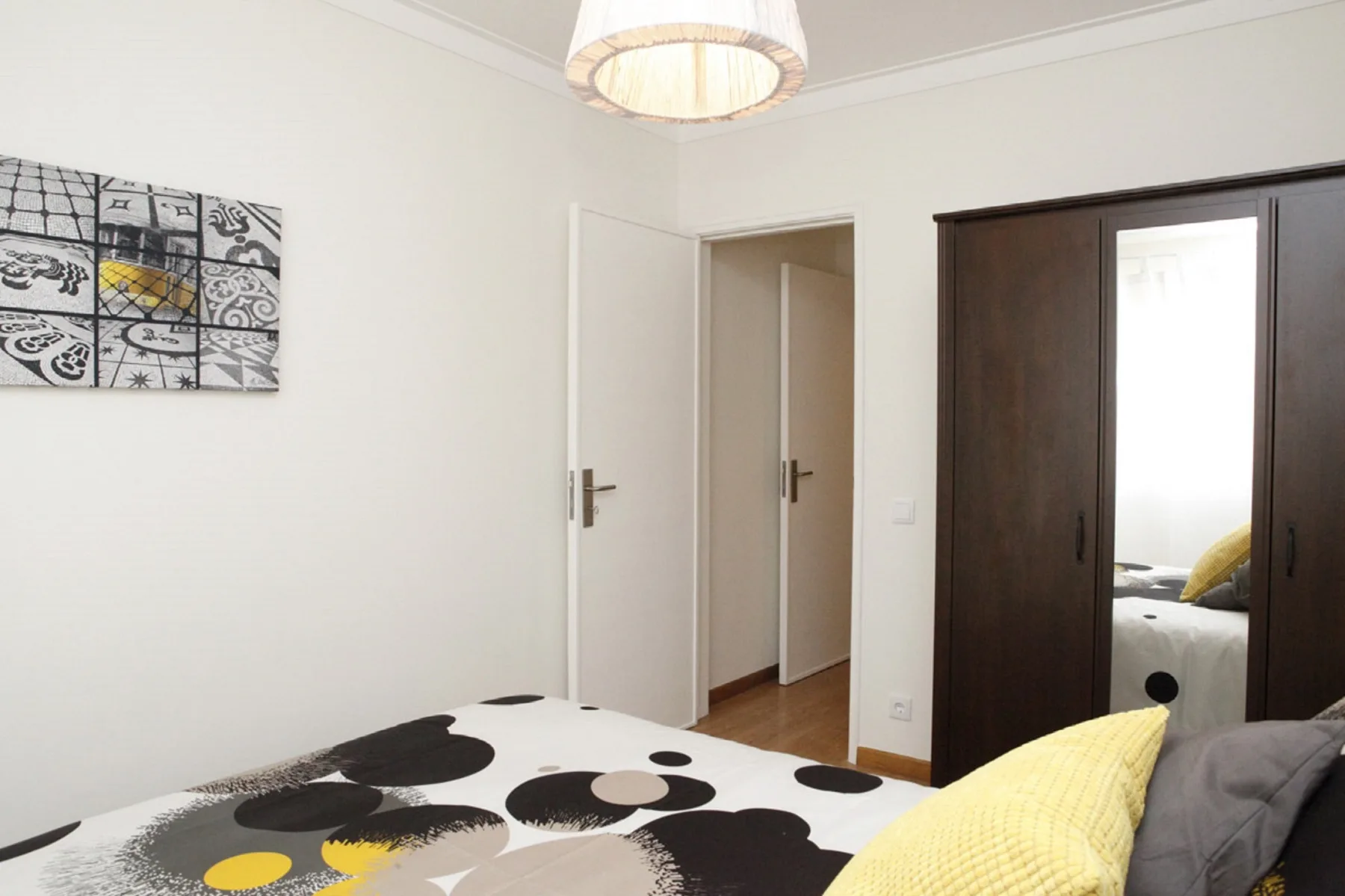 A bedroom with patterned bedding and a dark wardrobe.